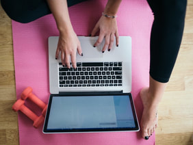 person working on laptop atop yoga mat