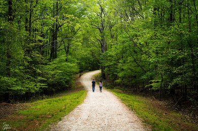 2 people walking down a path in the forest